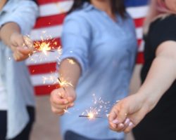 Weman holding sparklers with american flag background