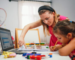 Education concept, little girl studying with friendly young home tutor during private lesson