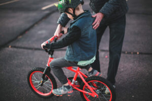 Man helps hold and steady his son as he learns to ride a bike.