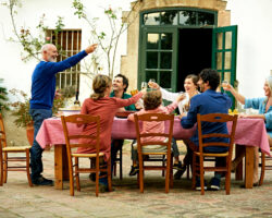 Side view of senior man raising toast to family at outdoor meal table in yard