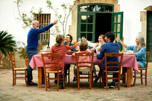 Side view of senior man raising toast to family at outdoor meal table in yard