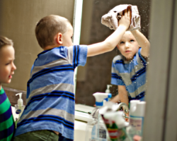 boy cleaning bathroom mirror