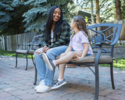 Nanny and child sitting in back yard