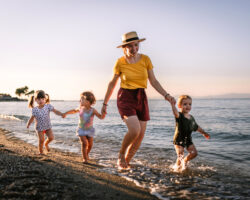 Nanny and children running on the beach