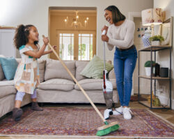 Nanny and child laughing while cleaning together during a summer organization game, turning chores into playful learning at home