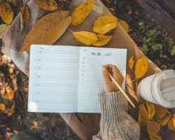 A person planning fall home organization and maintenance tasks in a notebook on a fall day.