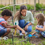 Governess gardening with two children, teaching hands-on spring learning and outdoor exploration