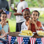 Nanny helping children enjoy a stress-free Fourth of July celebration with family, food, and patriotic decorations outdoors.