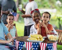 Nanny helping children enjoy a stress-free Fourth of July celebration with family, food, and patriotic decorations outdoors.